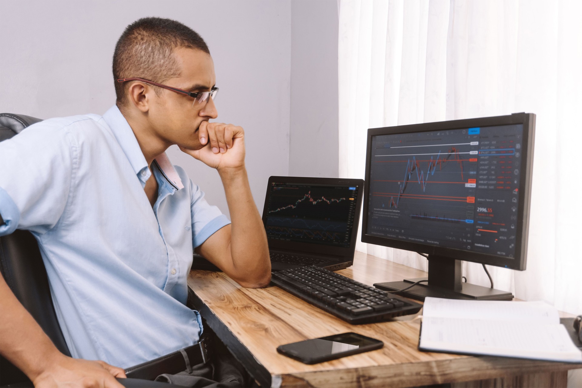 Young hispanic man viewing a graph on a computer. Latinx man invests in the stock market and studies trader.